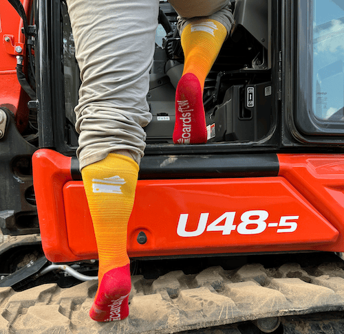 Man climbing into excavator wearing CardsFTW branded socks