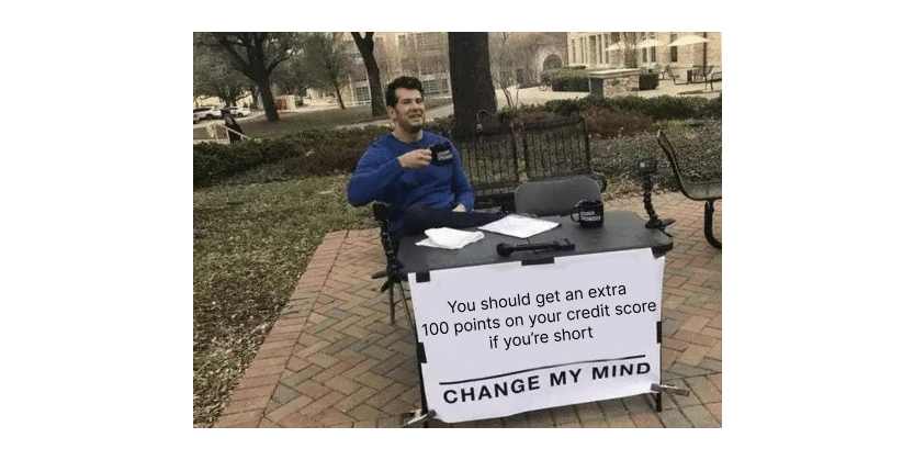 Image of man drinking coffee at a table outside with a sign that states "You should get an extra 100 points on your credit score if you're short - change my mind."