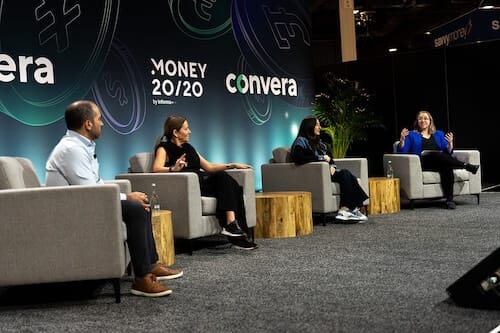 Four people, three women and a man, sitting in chairs on a stage on a panel.