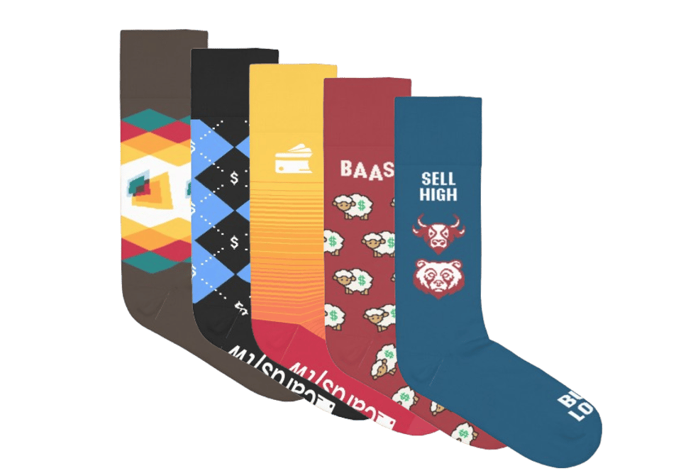 Image of the Goldman sock collection, featuring five colorful pairs of socks with unique financial-themed designs. From left to right: a geometric pattern with earthy tones, blue argyle with dollar signs, a yellow sock with a wallet icon, a red sock with ‘BAAS’ text and sheep holding money, and a teal sock featuring bull and bear market icons with the phrases ‘SELL HIGH’ and ‘BUY LOW.’