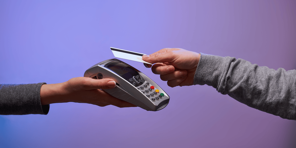 Image of a credit card being tapped on a handheld credit card device