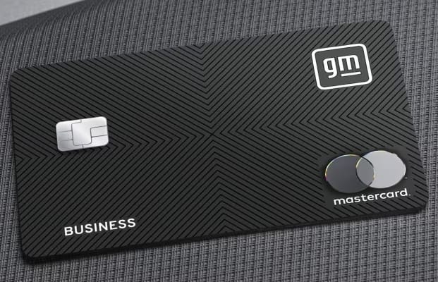 A black credit card with radiating lines. The GM logo is in the top right, the Mastercard logo is in the bottom right, and the word "business" is on the bottom left. The card is on a gray background that looks like the fabric of a car seat.